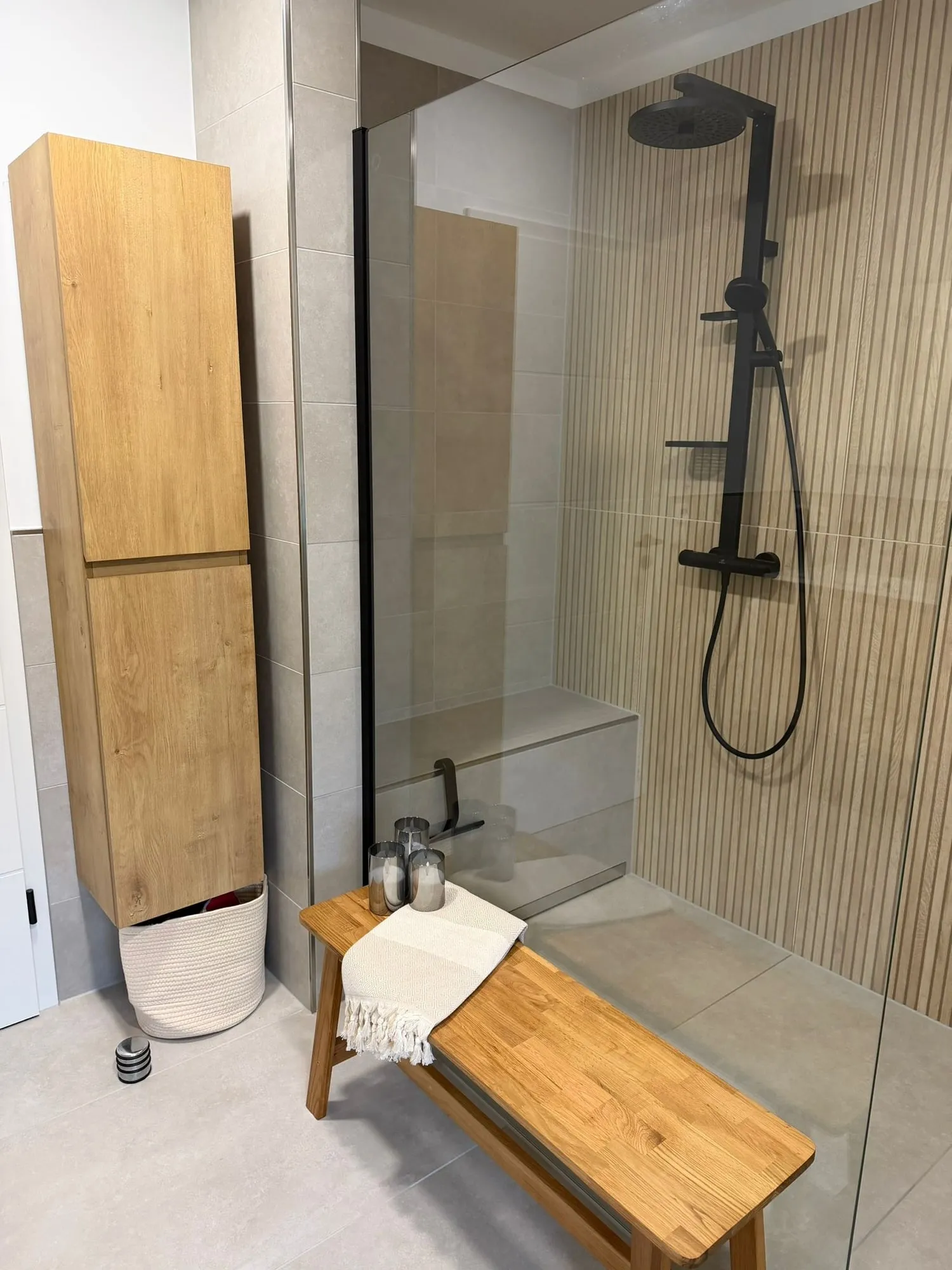Bodengleiche Dusche mit Glaswand, Holzbank und Rillenfliesen an der Wand