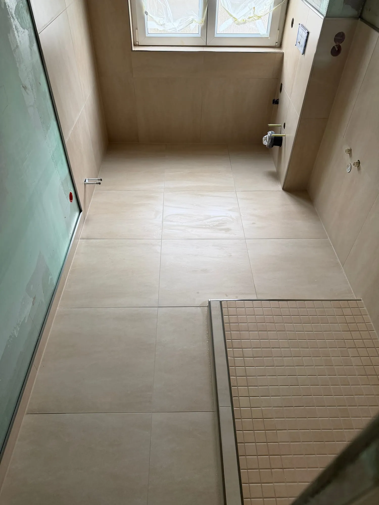 Langes Bad mit durchgehendem Boden in Großformat und bodengleicher Dusche unter dem Fenster